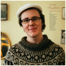 A young man with a sixpence and glasses, Jonas Sjøvaag, posing on the front of the Navyelectre album "Large Ensemble"